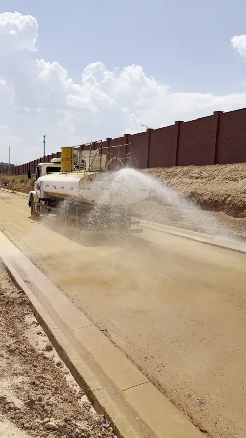 Jato de água do caminhão Pipa umedecendo a via ao lado do meio-fio